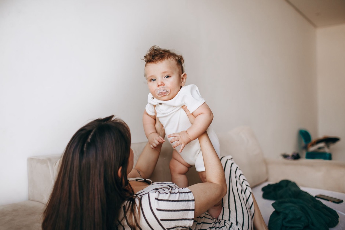 Kinder Schlafgewohnheiten: Baby in white onesie holding pacifier